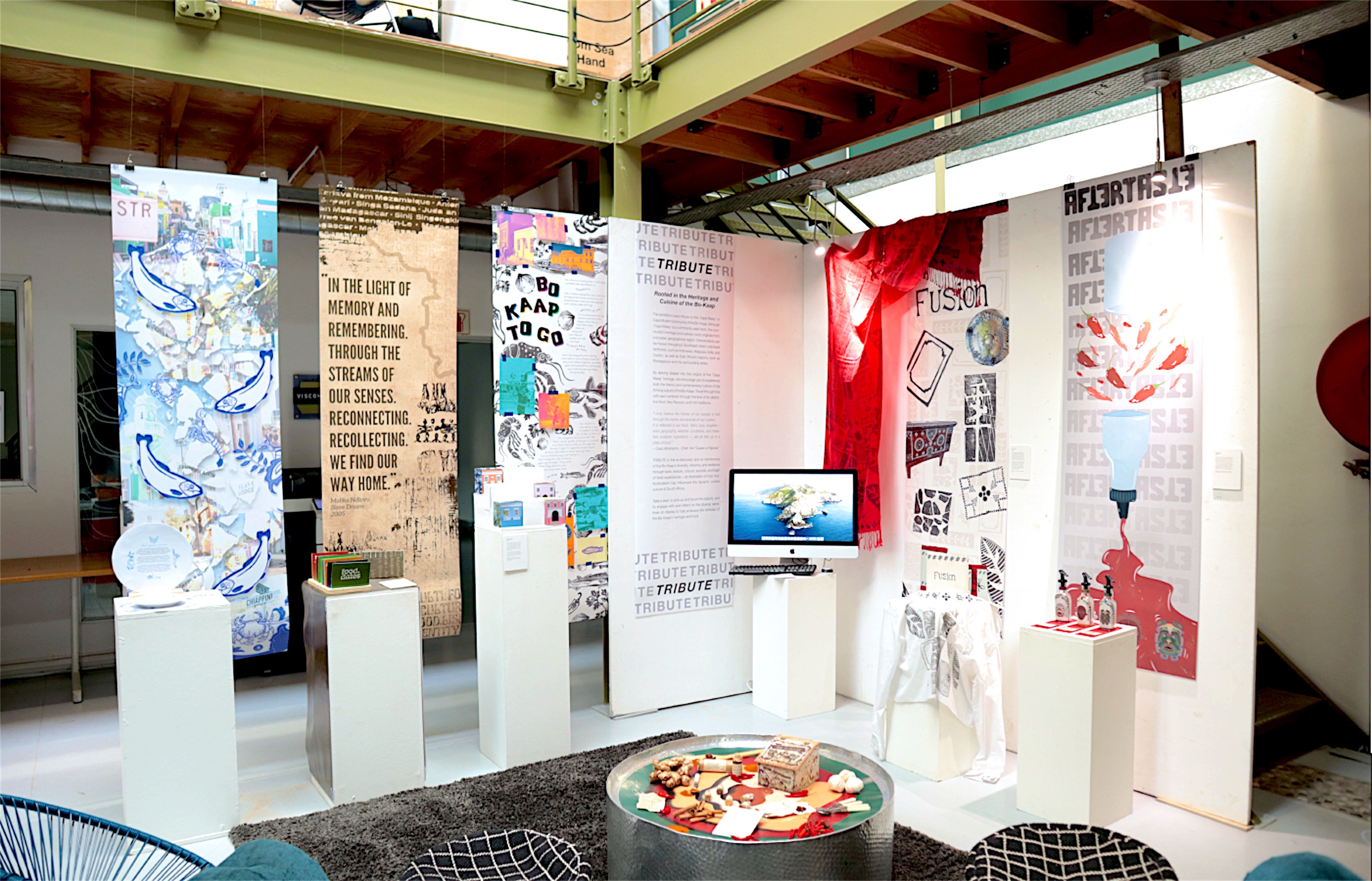 The Aftertaste exhibition space with printed banners, plinths, a screen and the hot sauce display