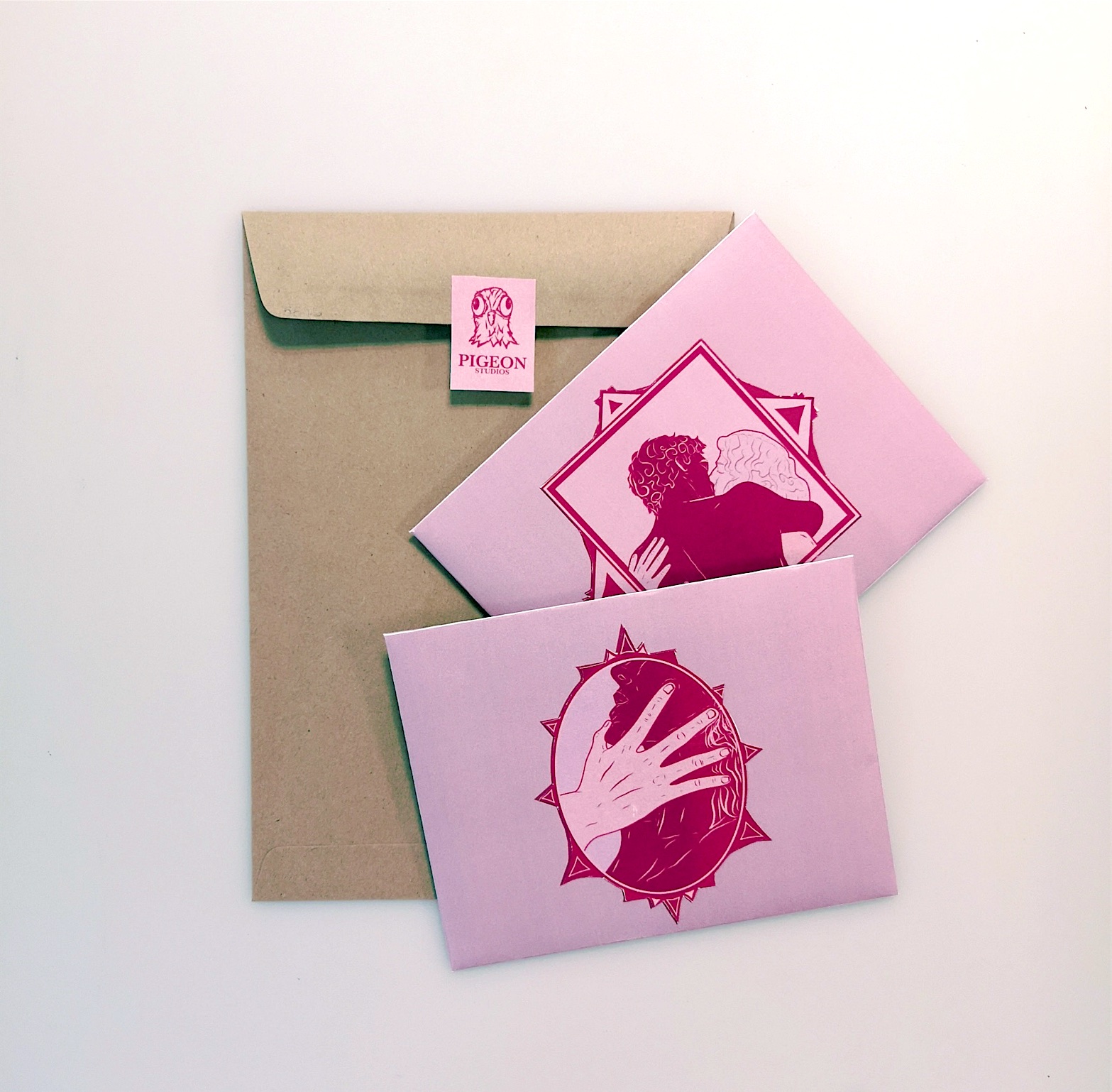 Pink illustrated cards with a Pigeon Studios seal on a kraft envelope