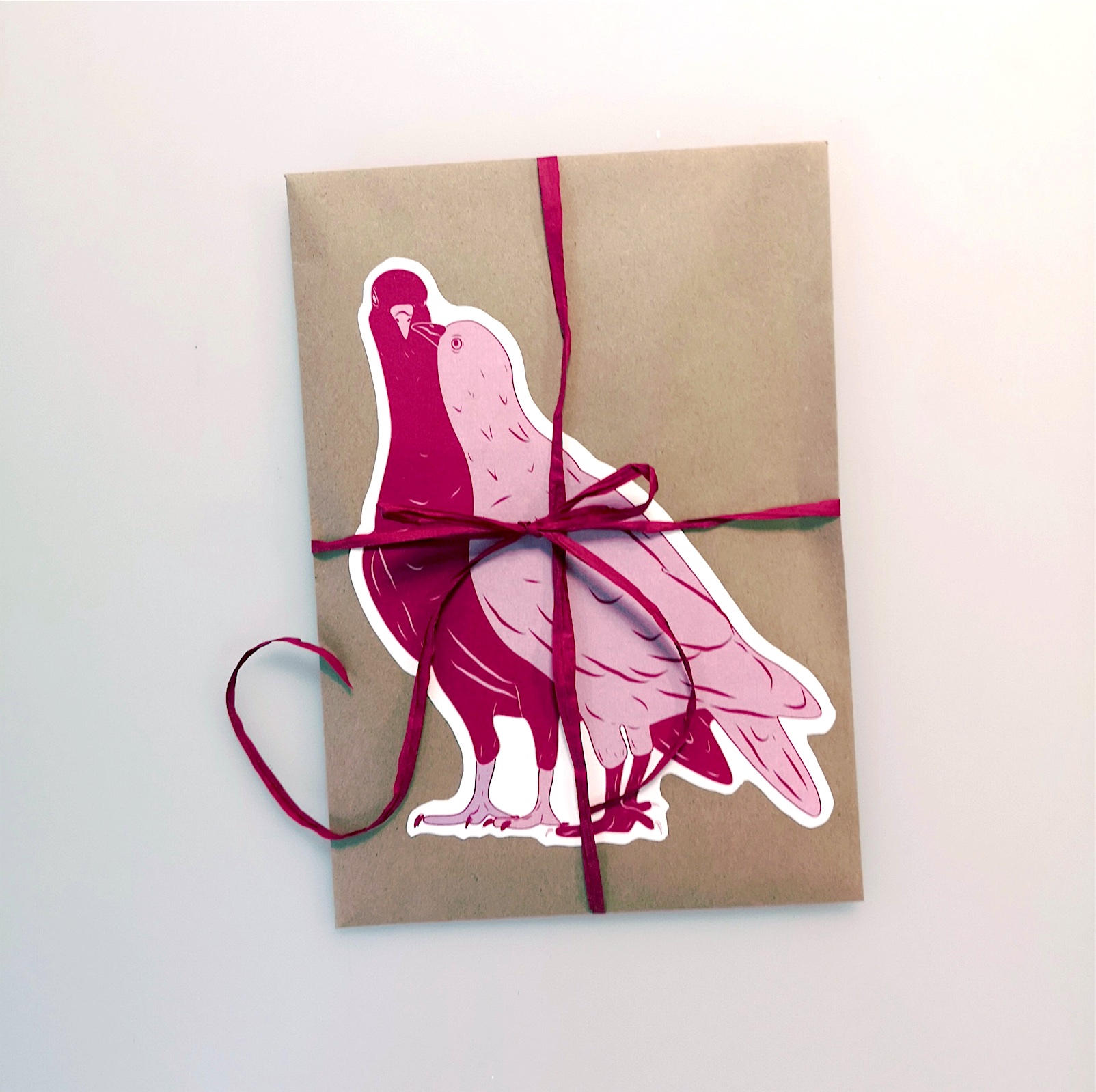 Kraft envelope tied with red ribbon and a pigeon sticker